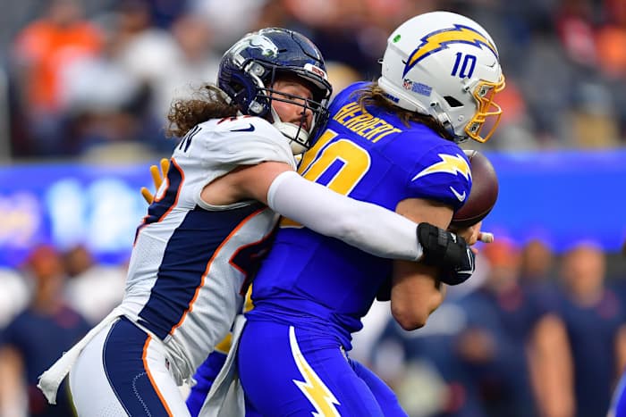 Los Angeles Chargers quarterback Justin Herbert is tackled by Denver Broncos linebacker Alex Singleton.